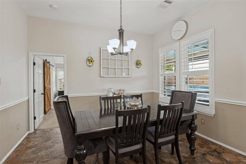 Vaulted ceiling with an attached chandelier, crown molding, and wainscoting