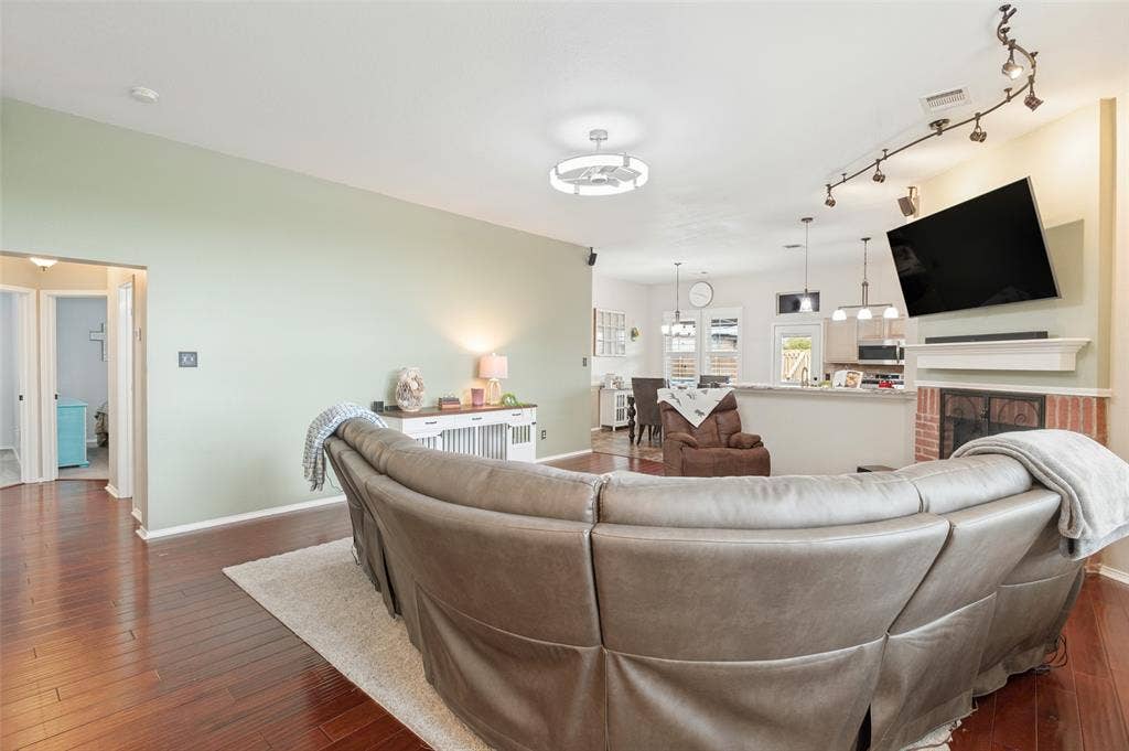Wood-finish flooring, recessed lighting, track lighting, ceiling fan light fixture, and a brick fireplace