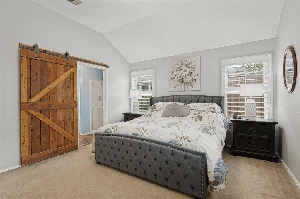 Vaulted ceiling, wood-finish barn door, and two windows with plantation shutters