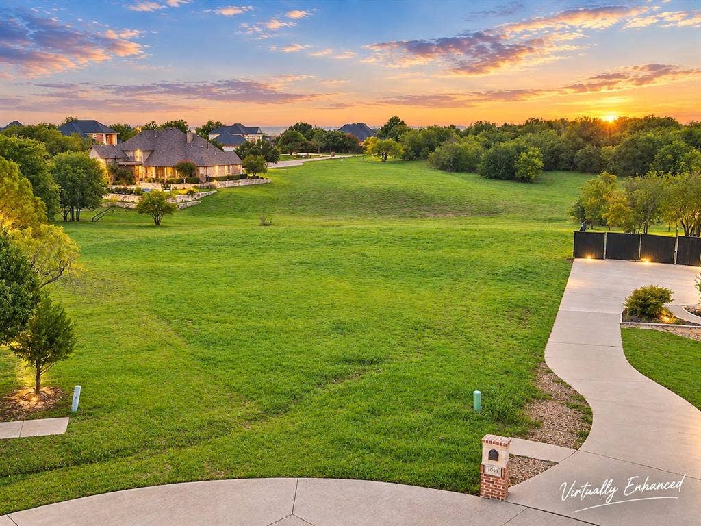 1036 Lighthouse Court, Grand Prairie, TX 75104 Expansive green space and a concrete driveway leading to a dark privacy fence with integrated lighting