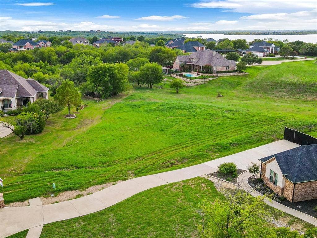 1036 Lighthouse Court, Grand Prairie, TX 75104 Expansive green land with a paved driveway and distant water body