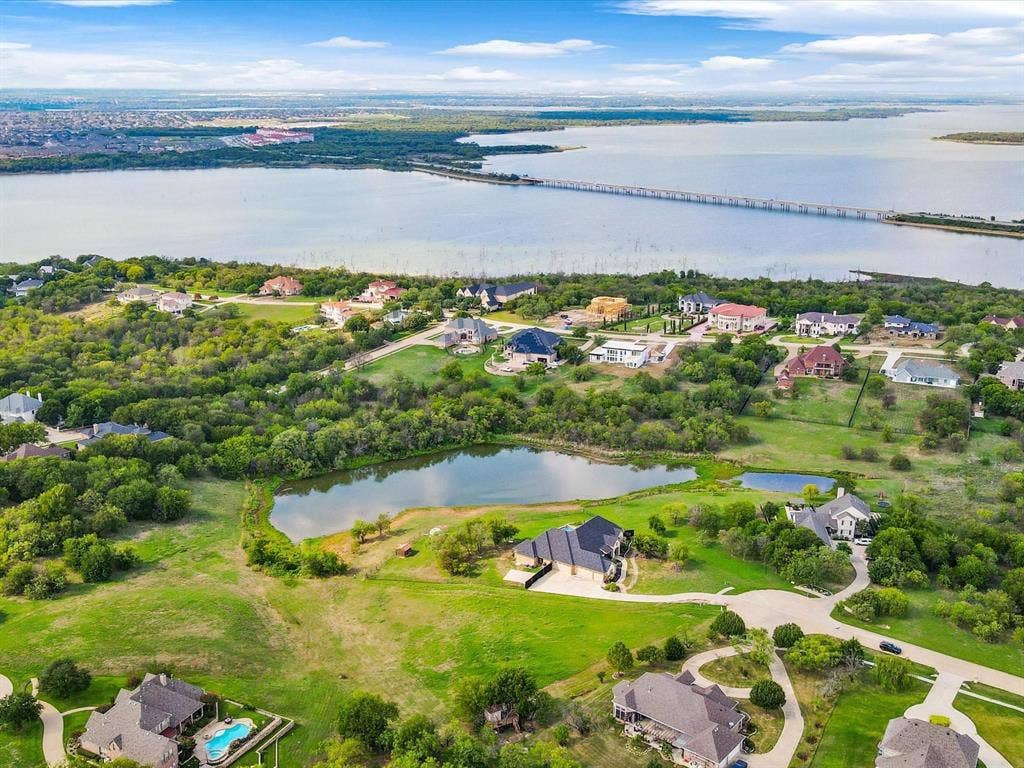 1036 Lighthouse Court, Grand Prairie, TX 75104 Expansive waterfront property featuring a private pond, lush green spaces, and a winding driveway