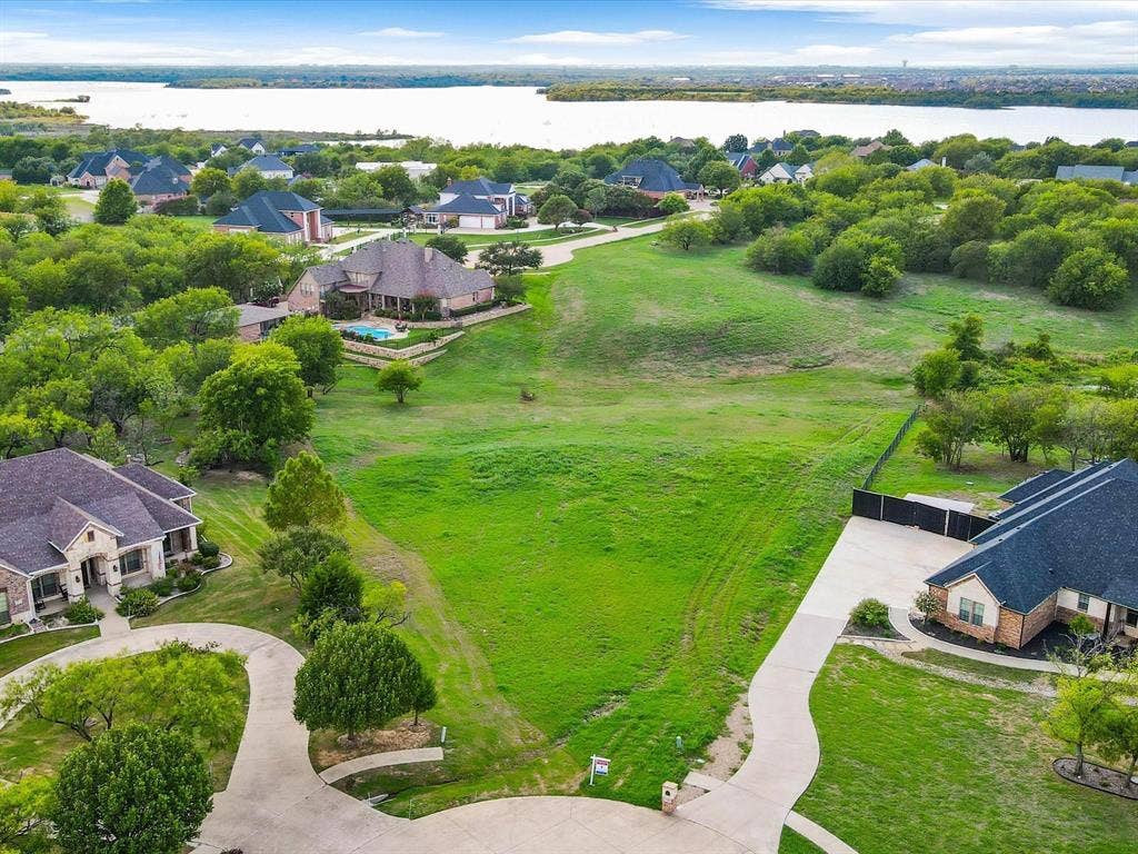 1036 Lighthouse Court, Grand Prairie, TX 75104 Expansive undeveloped lot with a gently sloping terrain, surrounded by mature trees, and featuring a concrete driveway