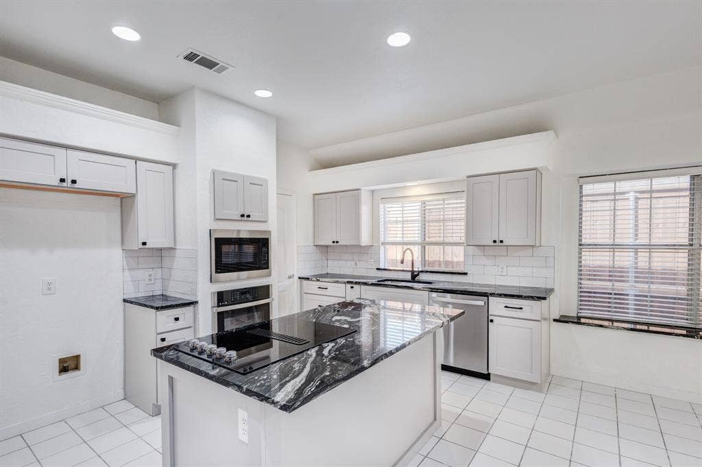 1306 Bentley Drive, Carrollton, TX 75006 Kitchen featuring a center island, black appliances, backsplash, and light tile patterned floors