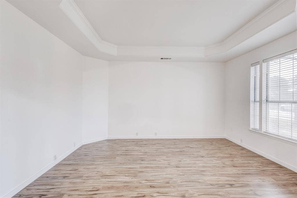 1306 Bentley Drive, Carrollton, TX 75006 Spare room with a raised ceiling, light hardwood / wood-style flooring, and ornamental molding