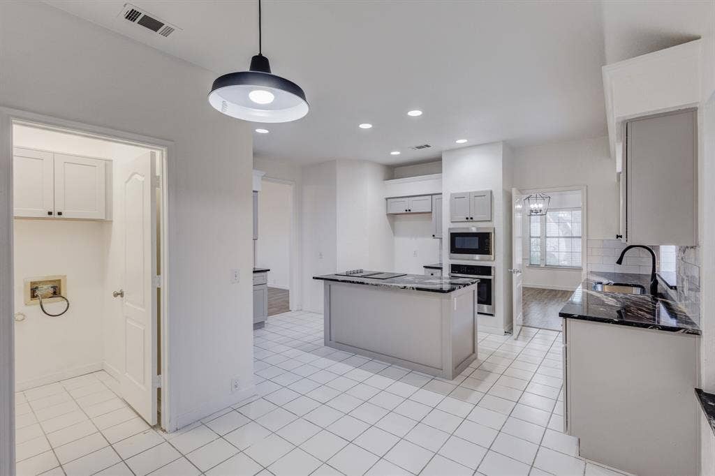 1306 Bentley Drive, Carrollton, TX 75006 Kitchen featuring appliances with stainless steel finishes, sink, pendant lighting, light hardwood / wood-style floors, and a kitchen island