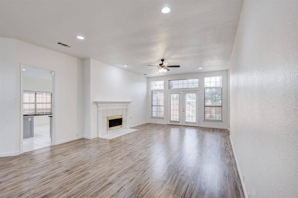 1306 Bentley Drive, Carrollton, TX 75006 Unfurnished living room featuring a tile fireplace, ceiling fan, and light hardwood / wood-style floors