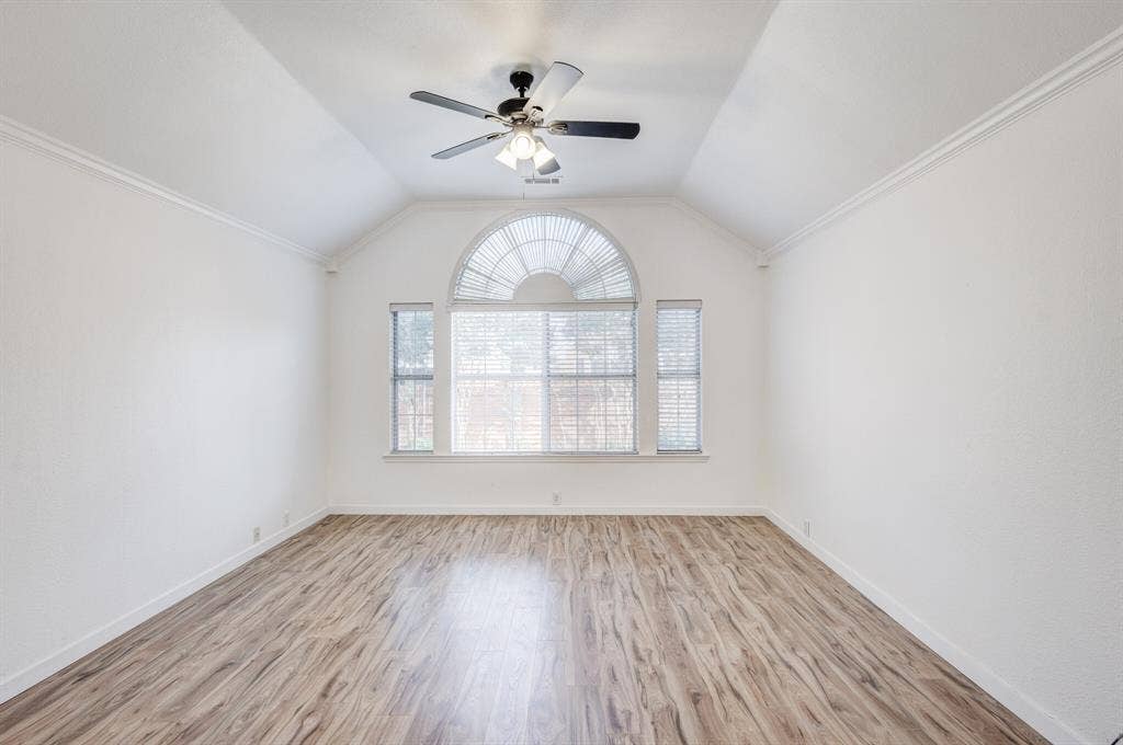 1306 Bentley Drive, Carrollton, TX 75006 Empty room with light hardwood / wood-style floors, ornamental molding, ceiling fan, and vaulted ceiling