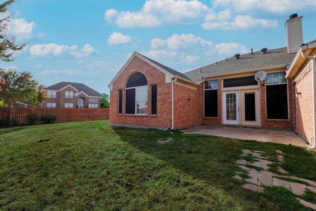 1306 Bentley Drive, Carrollton, TX 75006 Back of property with a patio and a lawn