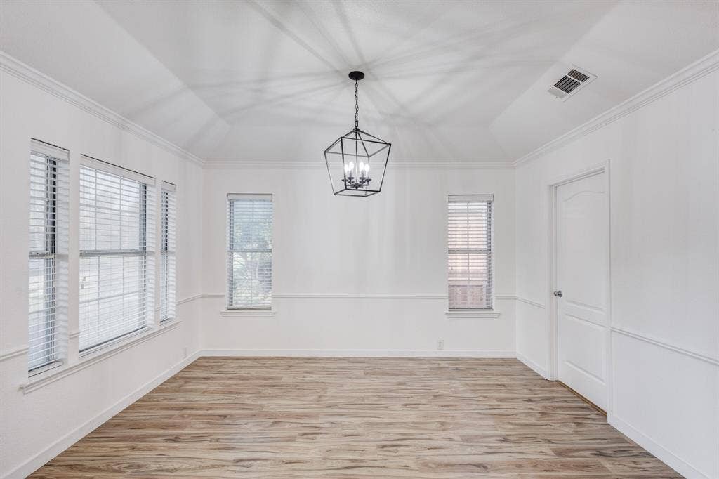 1306 Bentley Drive, Carrollton, TX 75006 Spare room featuring an inviting chandelier, ornamental molding, lofted ceiling, and light hardwood / wood-style floors