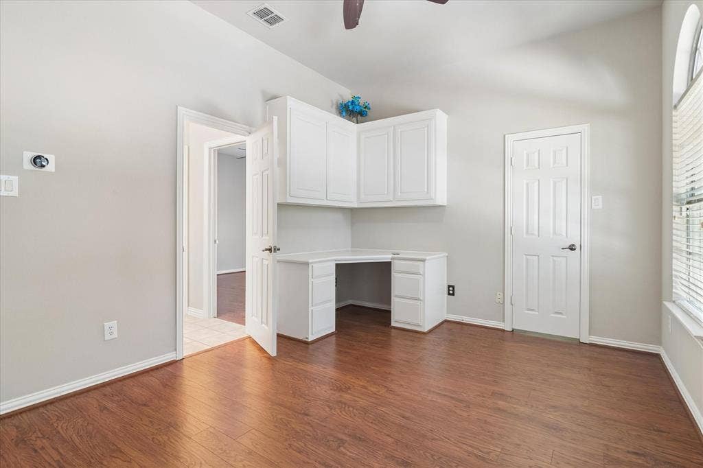 8323 Albritton Drive, Frisco, TX 75036 Built-in corner desk with upper and lower cabinetry, wood-finish flooring, vaulted ceiling, and an arched window