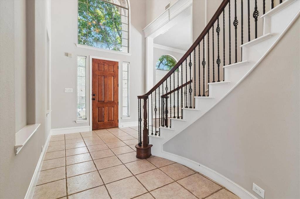 8323 Albritton Drive, Frisco, TX 75036 Two-story foyer with a natural wood paneled door, arched transom window, and tile flooring