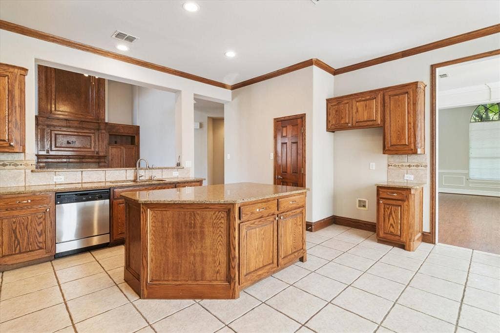 8323 Albritton Drive, Frisco, TX 75036 Kitchen featuring an island with wood-finish cabinetry, tile flooring, built-in stainless steel dishwasher, and stone countertops
