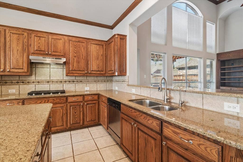 8323 Albritton Drive, Frisco, TX 75036 Kitchen featuring wood cabinetry, granite countertops, tile flooring, a stainless steel double basin sink, and a stainless steel dishwasher