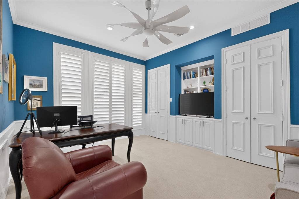 4536 Briar Oaks Circle, Dallas, TX 75287 Custom built-in shelving, white plantation shutters, decorative panel doors, crown molding, and a modern ceiling fan with integrated lighting