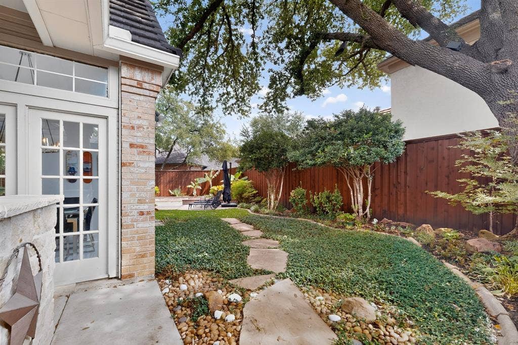 4536 Briar Oaks Circle, Dallas, TX 75287 Brick exterior with stone accents, French doors, mature trees, wood fencing, and a stone-paver pathway