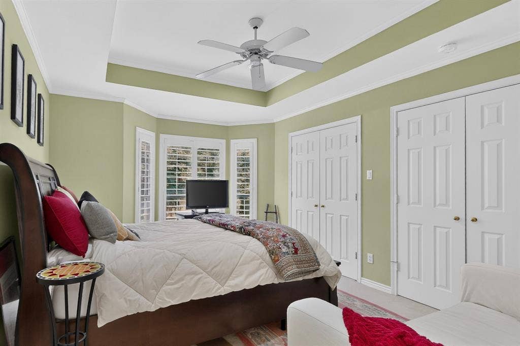 4536 Briar Oaks Circle, Dallas, TX 75287 Tray ceiling with a ceiling fan, bay window with plantation shutters, and two sets of double panel doors