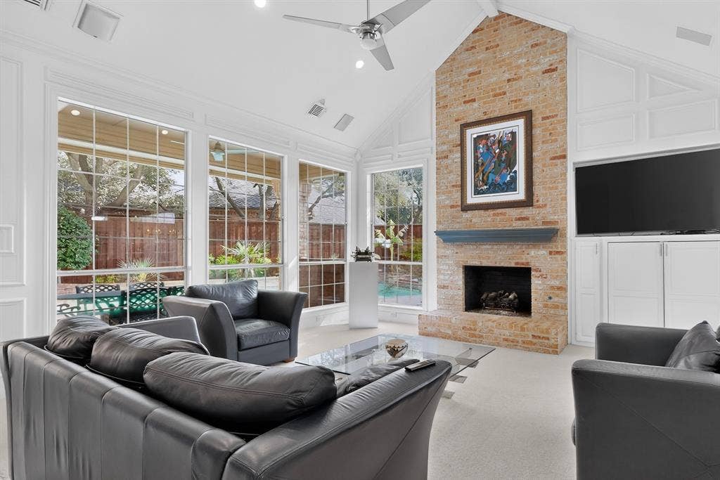 4536 Briar Oaks Circle, Dallas, TX 75287 Vaulted ceiling with exposed beam, full-height brick fireplace, built-in cabinetry, and expansive windows