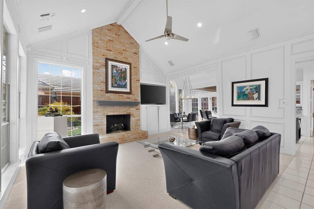 4536 Briar Oaks Circle, Dallas, TX 75287 Vaulted ceiling with a contemporary ceiling fan, brick fireplace with mantel, built-in cabinetry, large windows, and tile flooring