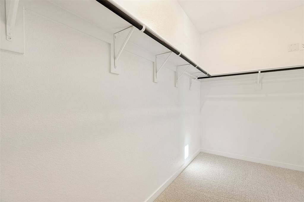 1006 Angel Street, Josephine, TX 75173 Room for Everything! - The primary suite's spacious walk-in closet features hanging rods and shelving along multiple walls, providing plenty of space to organize clothing, shoes, and accessories while keeping everything within easy reach.