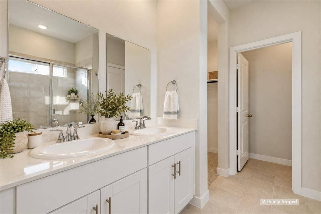 1006 Angel Street, Josephine, TX 75173 Your Personal Space to Refresh & Recharge! - The bright primary bathroom features dual sinks, white shaker-style cabinetry, sleek chrome fixtures, and generous vanity counter space. A separate glass-enclosed shower and private water closet complete this functional ensuite retreat.