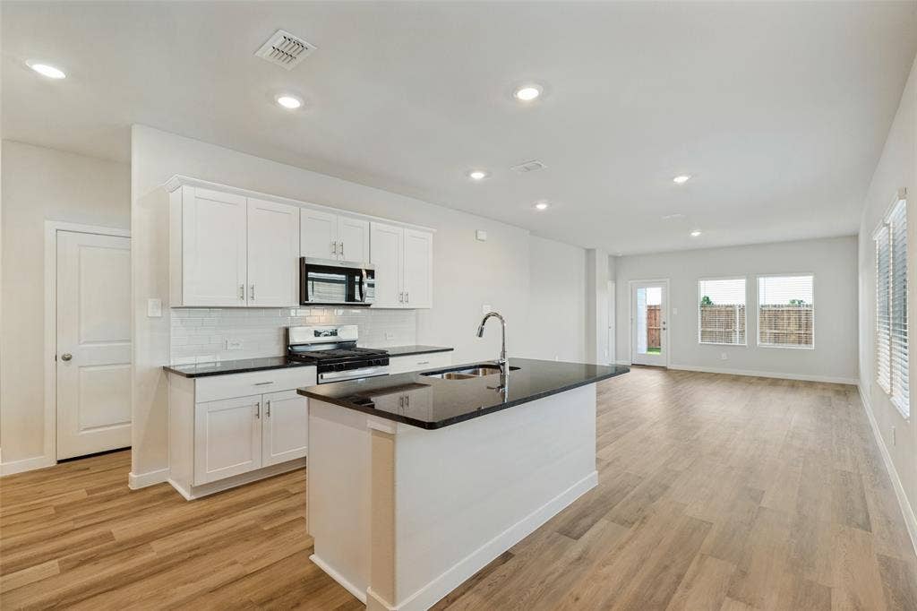 1006 Angel Street, Josephine, TX 75173 Stylish Finishes & an Open, Functional Layout! - Crisp white cabinetry contrasts beautifully with dark granite countertops, while stainless steel appliances and recessed lighting complete the modern look. The spacious island provides additional prep space and casual seating opportunities.