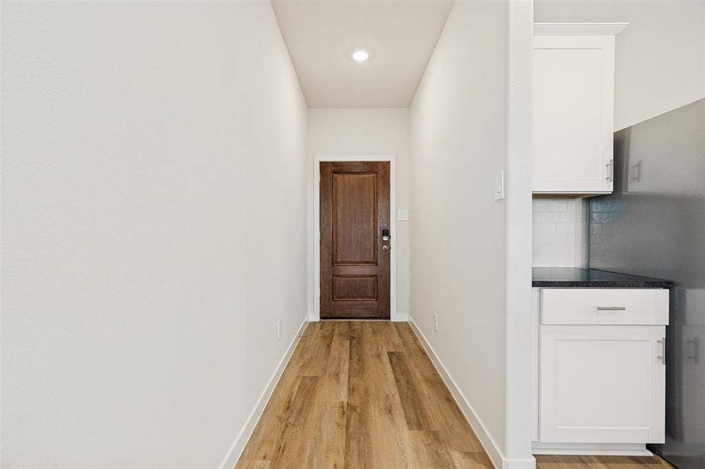 1006 Angel Street, Josephine, TX 75173 A Warm Welcome Home! - A rich stained front door opens to a bright entry hallway featuring attractive executive vinyl plank flooring, crisp white walls, and recessed lighting, setting the tone for the home's fresh, modern interior.