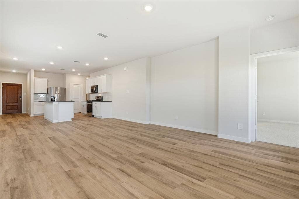 1006 Angel Street, Josephine, TX 75173 One Seamless Living Space! - Enjoy the convenience of an open-concept floor plan that brings together the family room, dining area, and kitchen. Continuous executive vinyl plank flooring and recessed lighting create a cohesive, inviting atmosphere throughout.