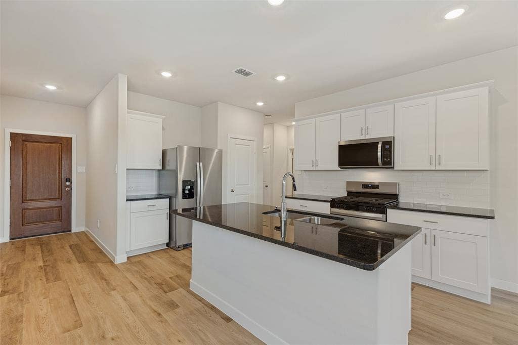 1006 Angel Street, Josephine, TX 75173 Everything You Need, Right Where You Need It! - Enjoy generous cabinet storage, expansive countertop space, and a thoughtfully arranged kitchen featuring a stainless steel refrigerator, gas range, built-in microwave, and a large island with an undermount sink.