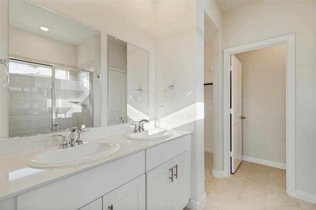 1006 Angel Street, Josephine, TX 75173 Double the Convenience! - Two separate sinks, generous vanity counter space, individual mirrors, and convenient cabinet storage make morning and evening routines easier in this bright, beautifully finished primary bathroom.