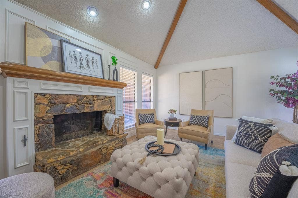 410 W Oak Street, Wylie, TX 75098 Stone fireplace with wood mantel, vaulted ceiling with exposed beams, recessed lighting, and wall-mounted windows