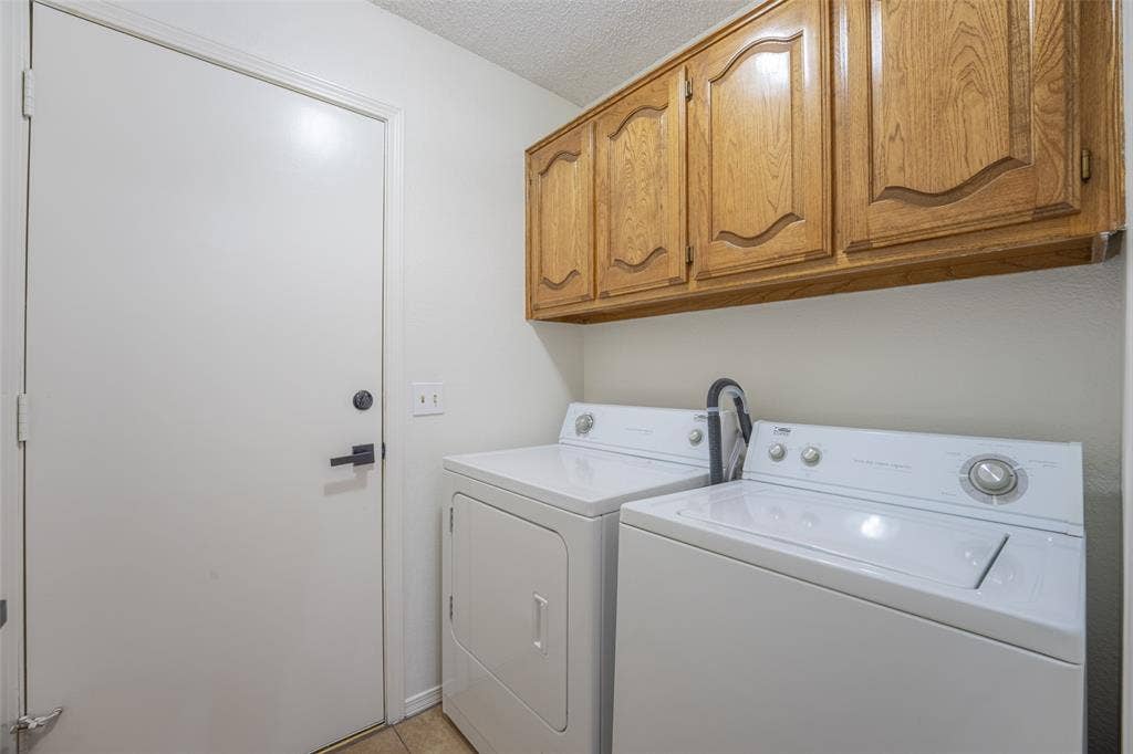 410 W Oak Street, Wylie, TX 75098 Laundry area featuring wood-finish cabinetry, tile flooring, and a solid core door