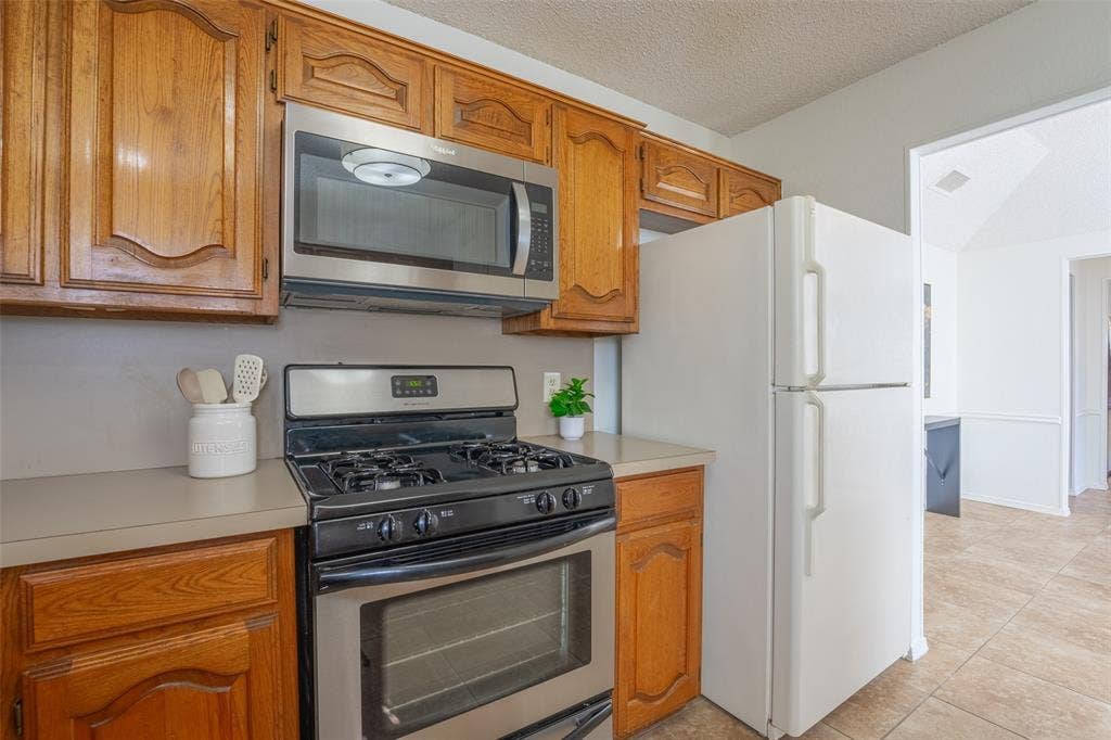 410 W Oak Street, Wylie, TX 75098 Kitchen with wood cabinetry, stainless steel microwave, and a gas range