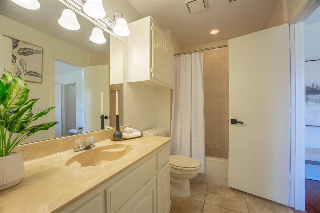 410 W Oak Street, Wylie, TX 75098 Bathroom featuring a full vanity with an integrated sink, overhead wall-mounted cabinetry, a shower-tub combination, and tiled flooring
