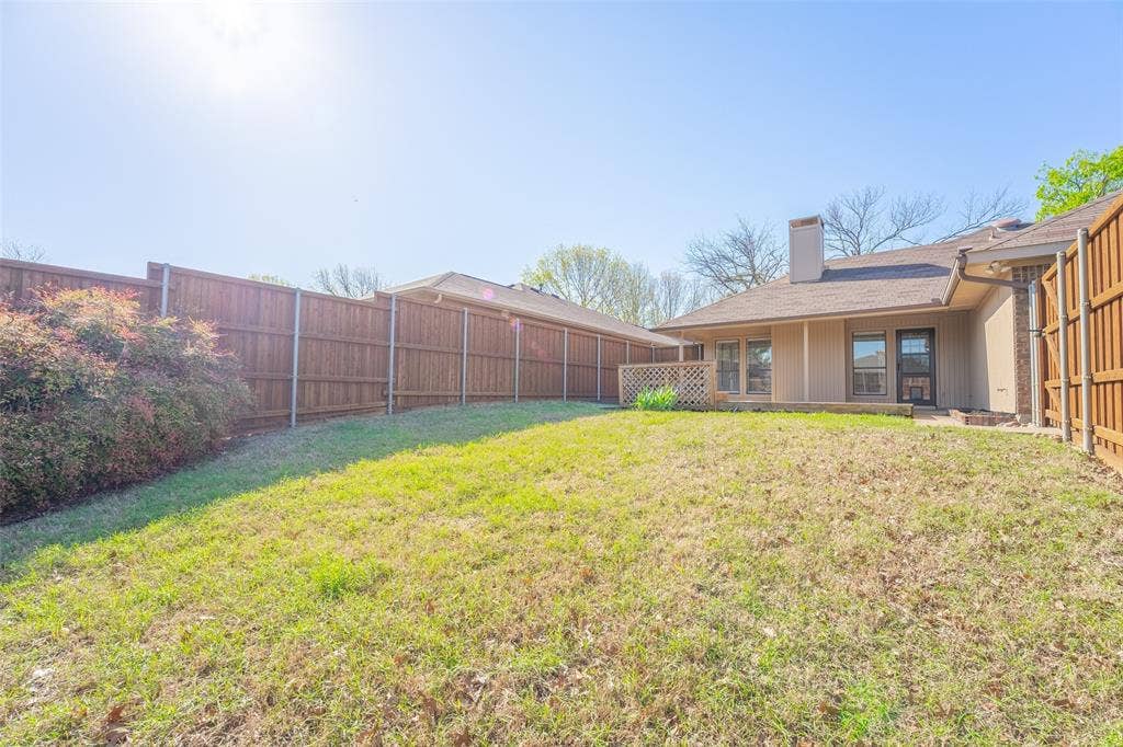 410 W Oak Street, Wylie, TX 75098 Expansive backyard featuring a wood privacy fence, mature perimeter shrubbery, and a multi-pane glass door