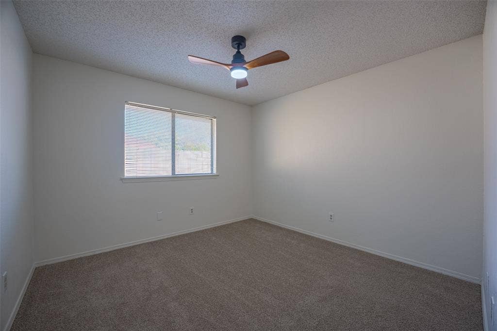 410 W Oak Street, Wylie, TX 75098 Neutral wall color, window with blinds, ceiling fan with integrated lighting, and carpet flooring
