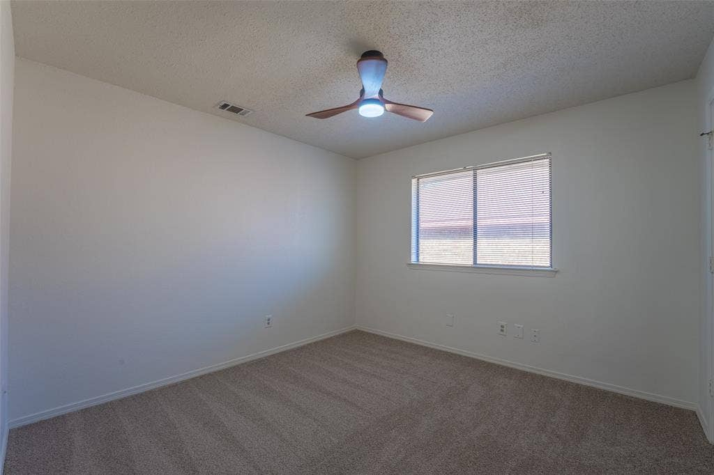 410 W Oak Street, Wylie, TX 75098 Neutral wall paint, textured ceiling, window with blinds, ceiling fan with integrated lighting, and carpet flooring