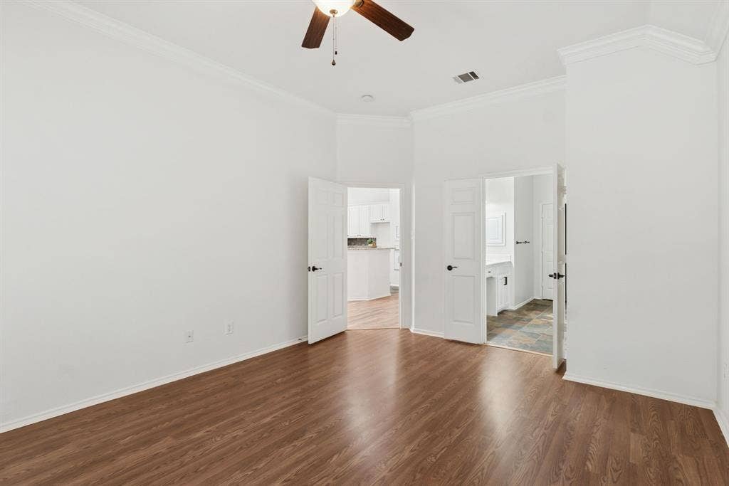 4816 Rockcreek Lane, Plano, TX 75024 Wood-finish flooring, crown molding, ceiling fan, and white paneled doors