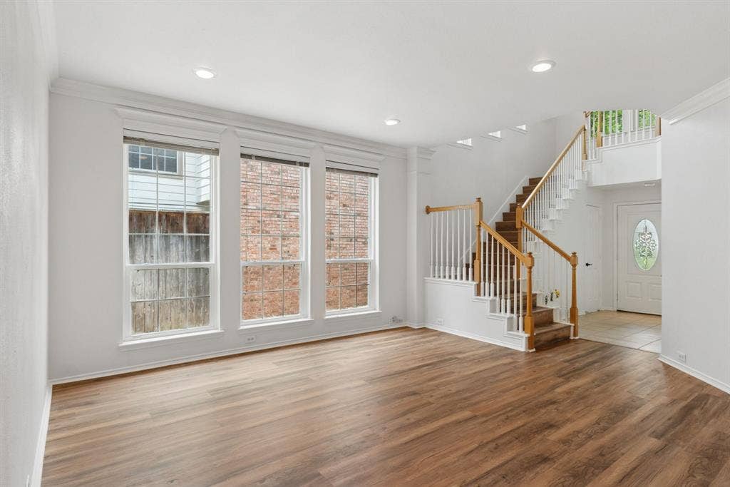 4816 Rockcreek Lane, Plano, TX 75024 Wood-finish flooring, recessed lighting, white wall paint, three large windows, and a staircase with wood handrails