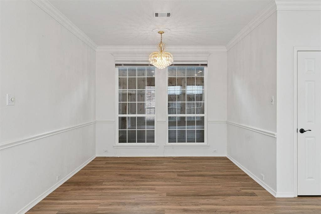 4816 Rockcreek Lane, Plano, TX 75024 Wood-finish flooring, crown molding, chair rail molding, clear paned windows, and a decorative chandelier