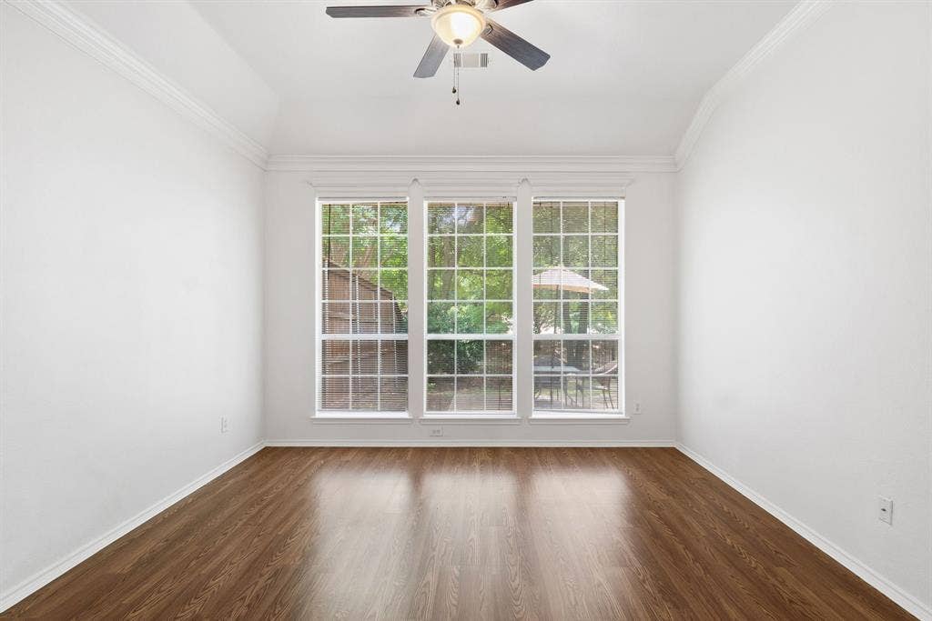 4816 Rockcreek Lane, Plano, TX 75024 Vaulted ceiling with crown molding, ceiling fan, wood-finish flooring, and a bank of three large windows