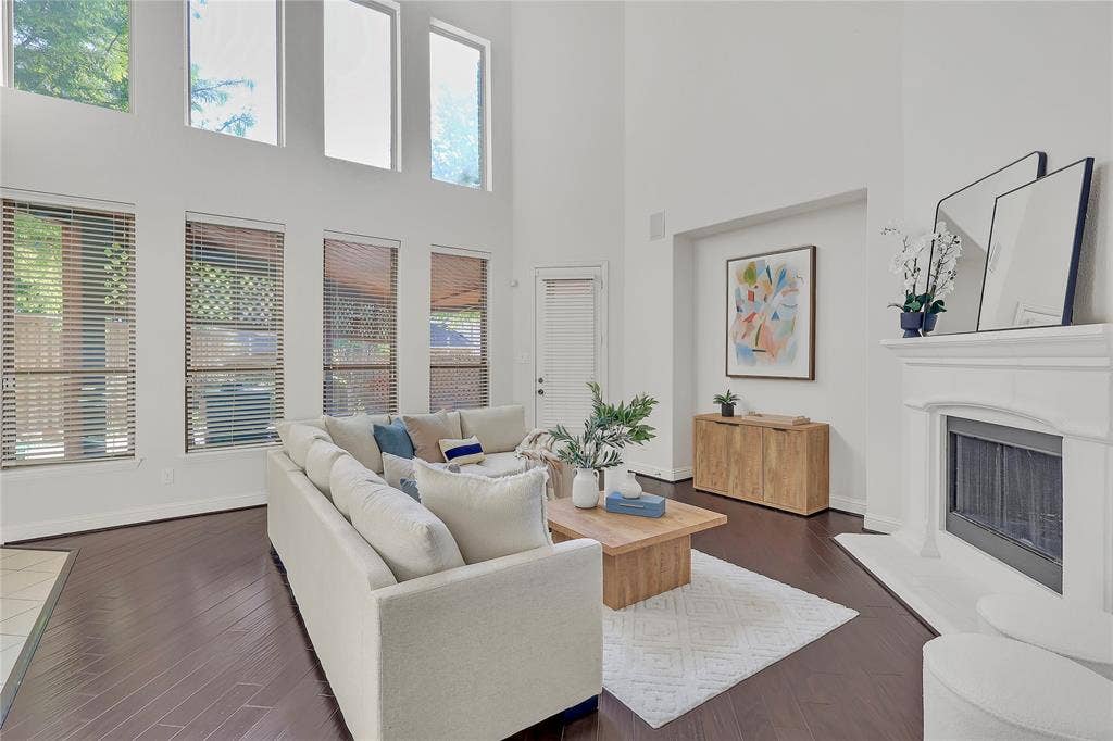 8730 Isaac Street, Plano, TX 75024 Living room with plenty of natural light, a towering ceiling, dark wood-style floors, and a fireplace with raised hearth