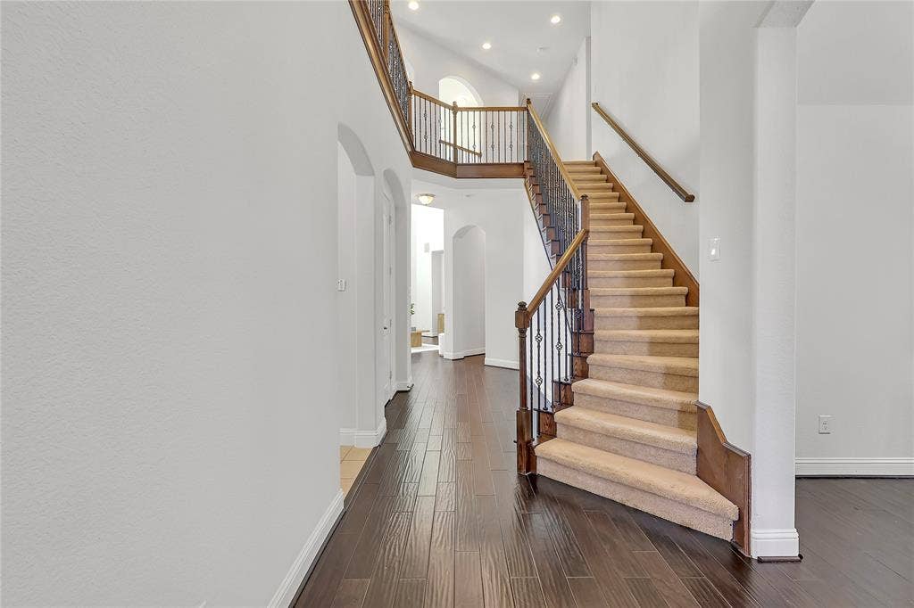 8730 Isaac Street, Plano, TX 75024 Stairway featuring arched walkways, a high ceiling, recessed lighting, and wood finished floors