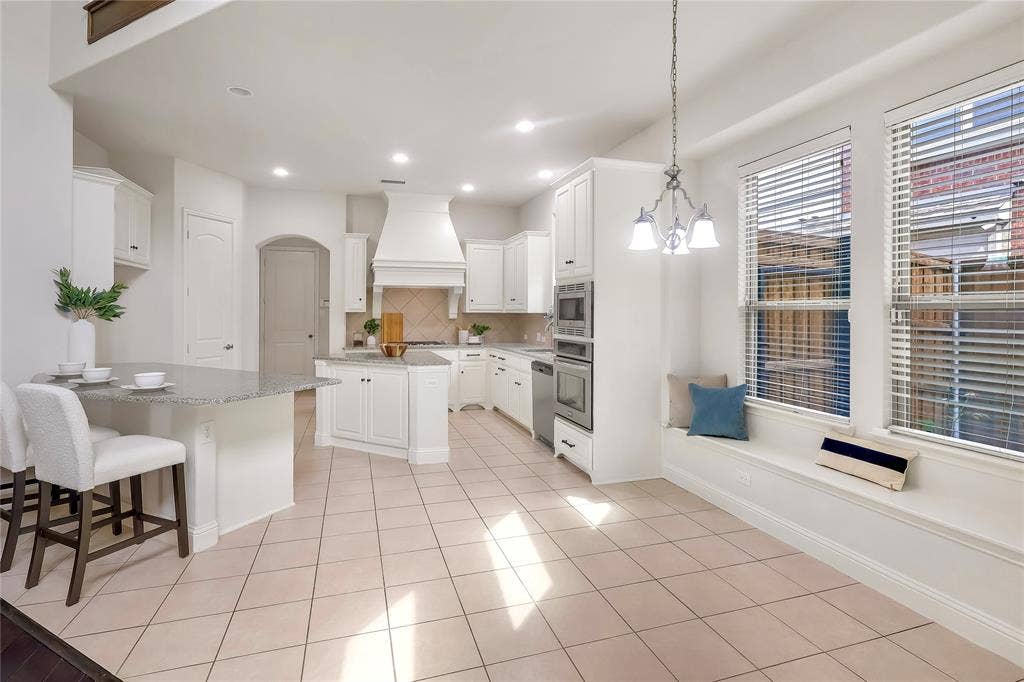 8730 Isaac Street, Plano, TX 75024 Kitchen with premium range hood, appliances with stainless steel finishes, decorative backsplash, a center island, and arched walkways
