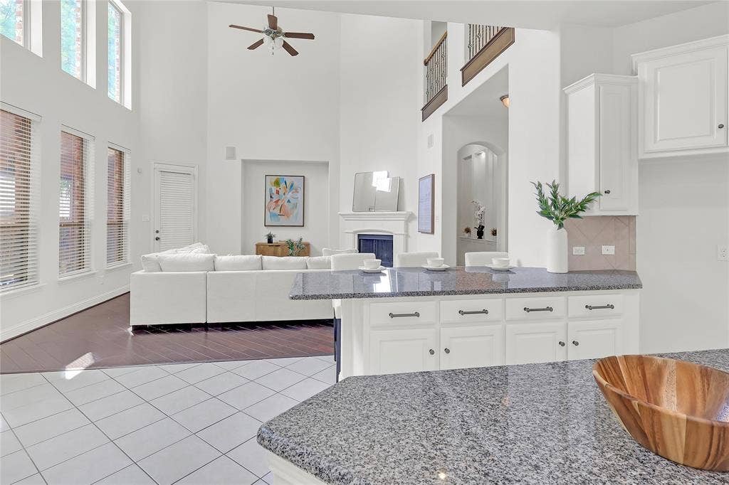 8730 Isaac Street, Plano, TX 75024 Kitchen featuring dark stone countertops, a towering ceiling, tile patterned floors, ceiling fan, and white cabinetry