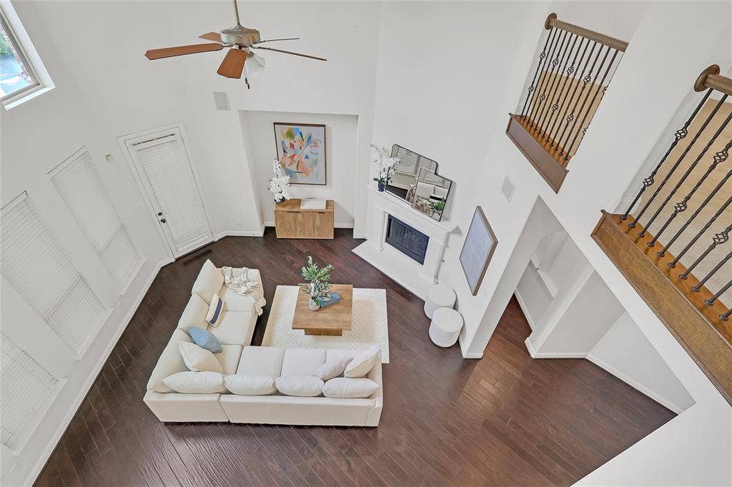 8730 Isaac Street, Plano, TX 75024 Living room featuring a towering ceiling, wood finished floors, a fireplace, stairs, and ceiling fan