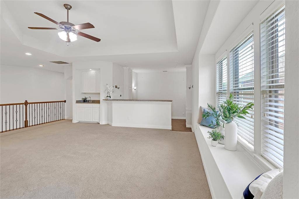 8730 Isaac Street, Plano, TX 75024 Unfurnished living room with light colored carpet, ceiling fan, a raised ceiling, and recessed lighting