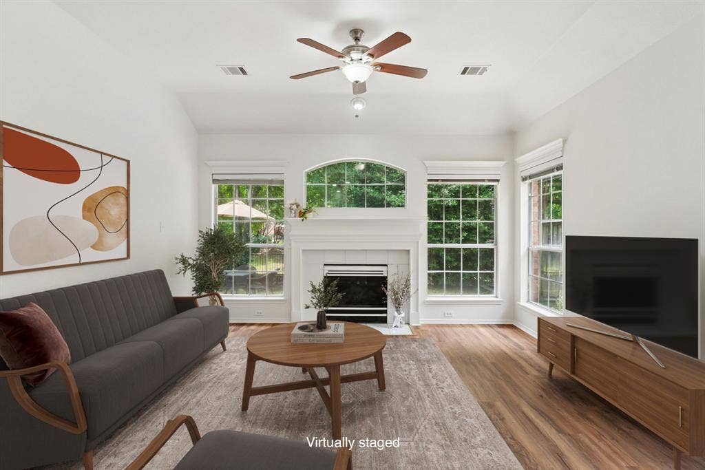 4816 Rockcreek Lane, Plano, TX 75024 Vaulted ceiling with a ceiling fan, fireplace with a mantel, wood-finish flooring, and multiple windows
