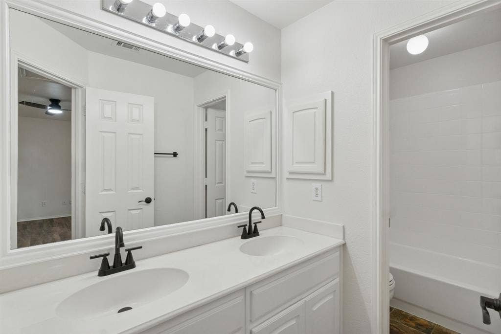 4816 Rockcreek Lane, Plano, TX 75024 Double vanity with white countertops, undermount sinks, and matte black fixtures