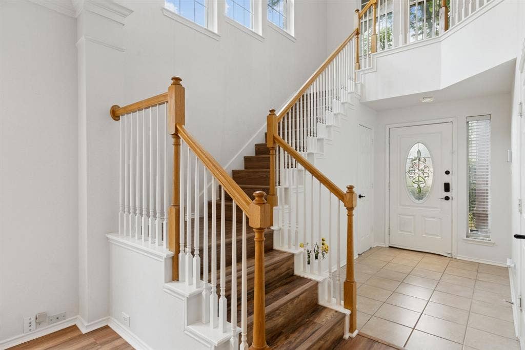 4816 Rockcreek Lane, Plano, TX 75024 Two-story entryway featuring a wood-finish staircase with white risers and balusters